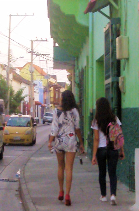 two women walking down the side walk of a city street