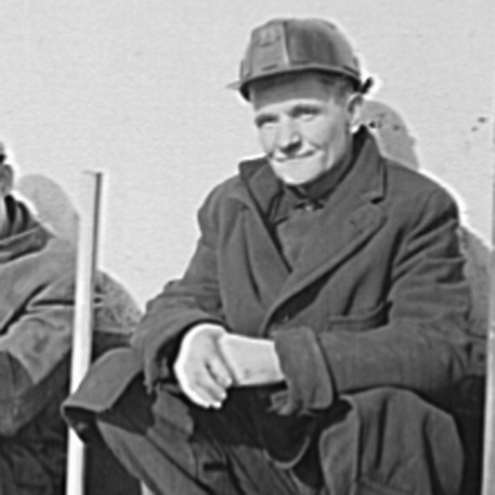 an old picture of two men sitting in front of a building