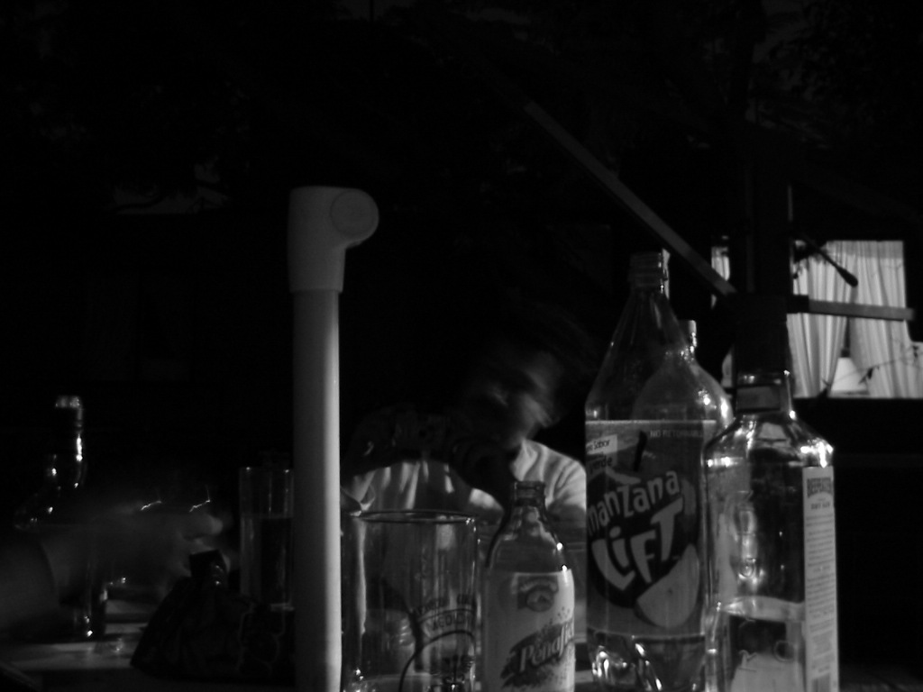 man in white shirt behind liquor bottles and glass