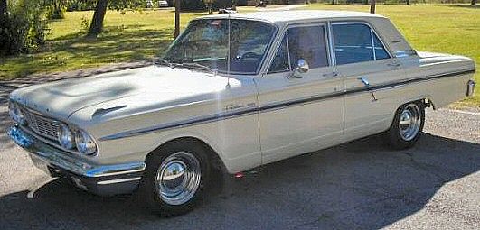 an old white car parked in the driveway