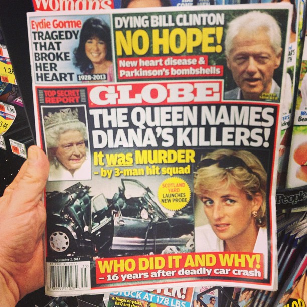 a person holds up the front cover of a news paper with pictures of prince and queen