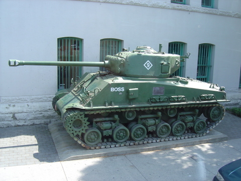 an old green military tank sitting in the middle of town