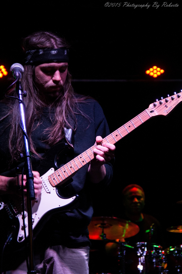 a man with long hair playing guitar at a band