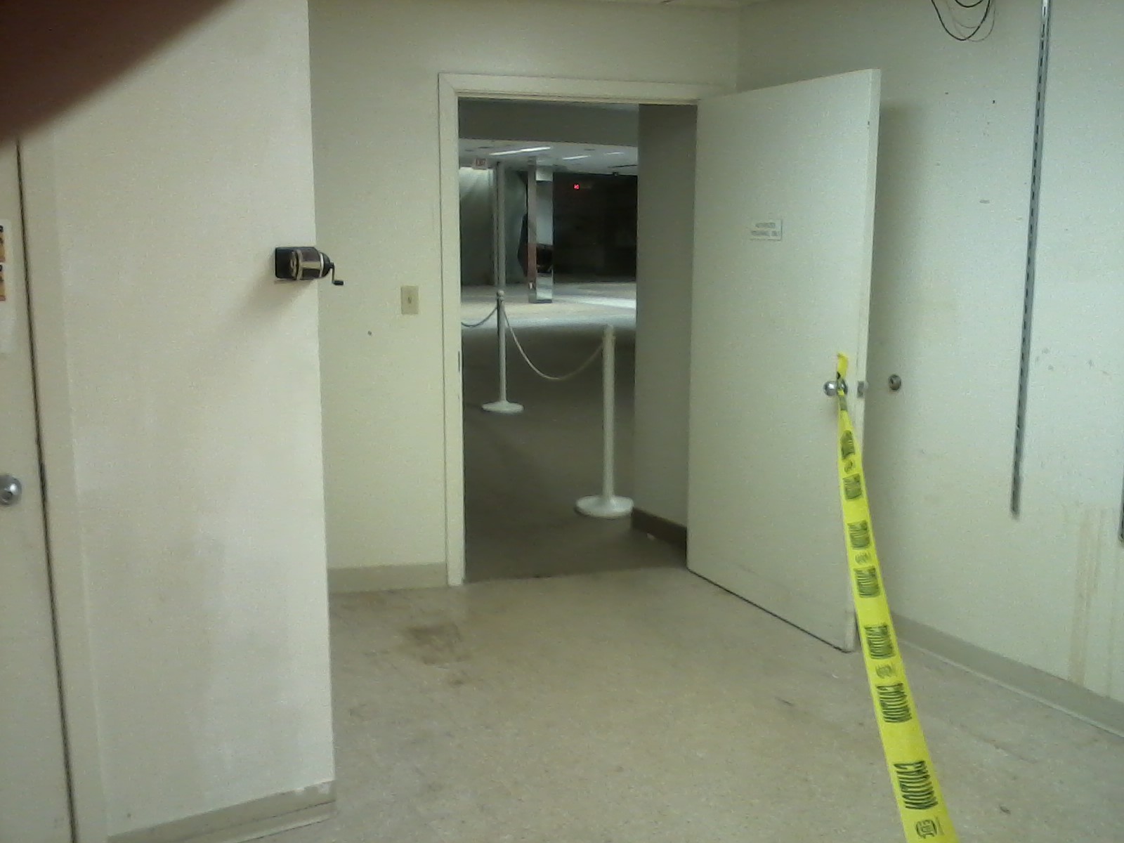 the open door of an empty room with yellow caution tape on the wall