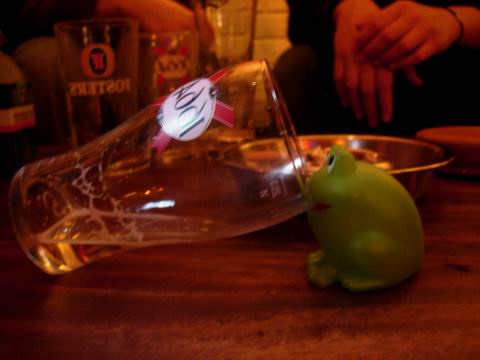 a small green toy pig in a glass cup