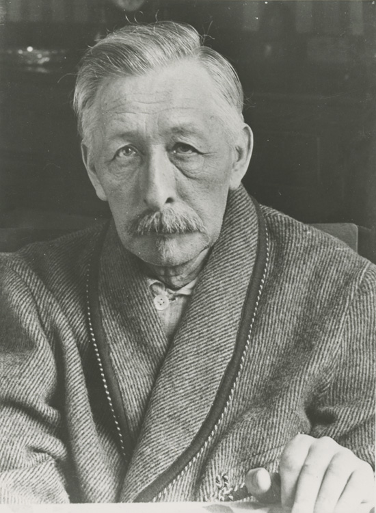 a man with a moustache and mustache, sitting and looking at the camera