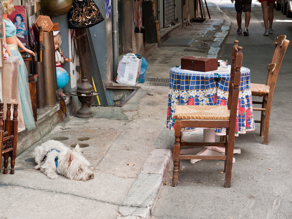 an old chair on the sidewalk in front of furniture stores