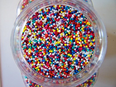small multi - colored sprinkles are in a clear container