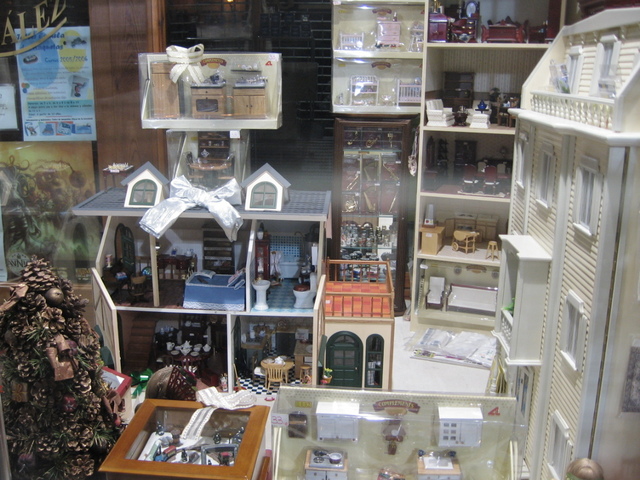 the display case is full of miniature model houses and doll furniture