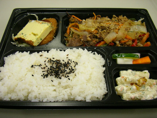 a black tray with white rice and meat on it