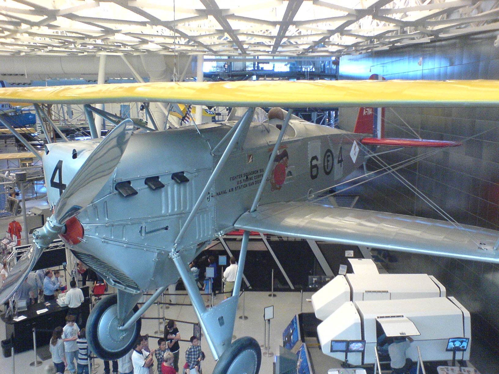 a small airplane hanging in a museum with people around