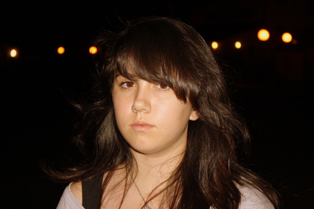 a young woman with long hair standing in the dark