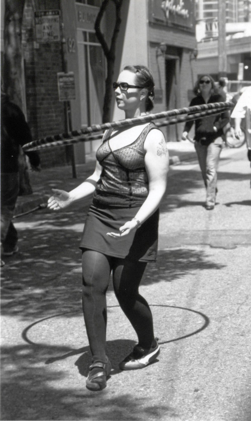 a woman balancing herself on a pole on the sidewalk