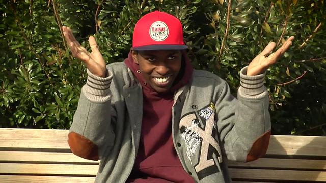 a young black man sitting on top of a wooden bench