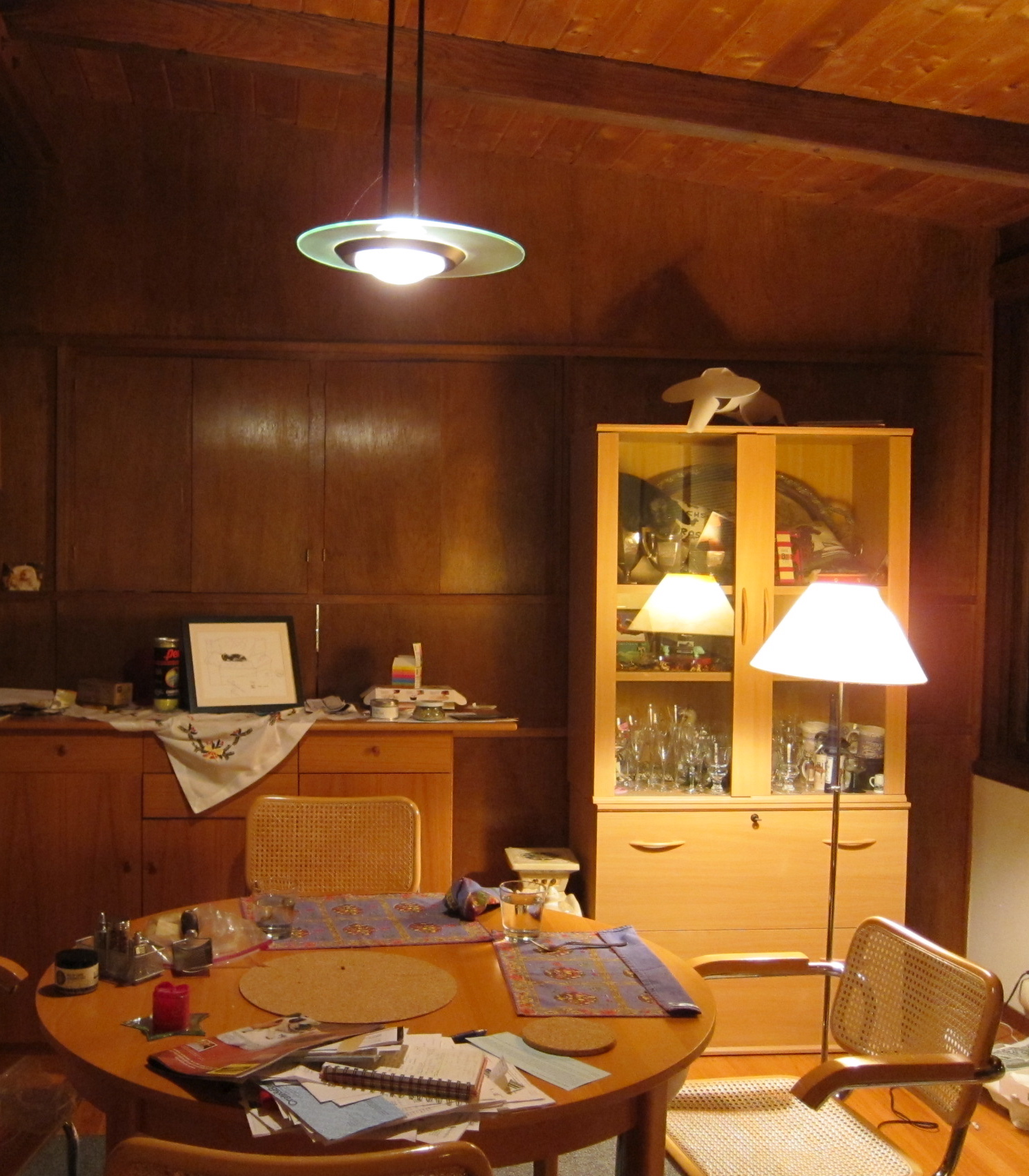 a wood paneled dining room with lots of clutter on the table