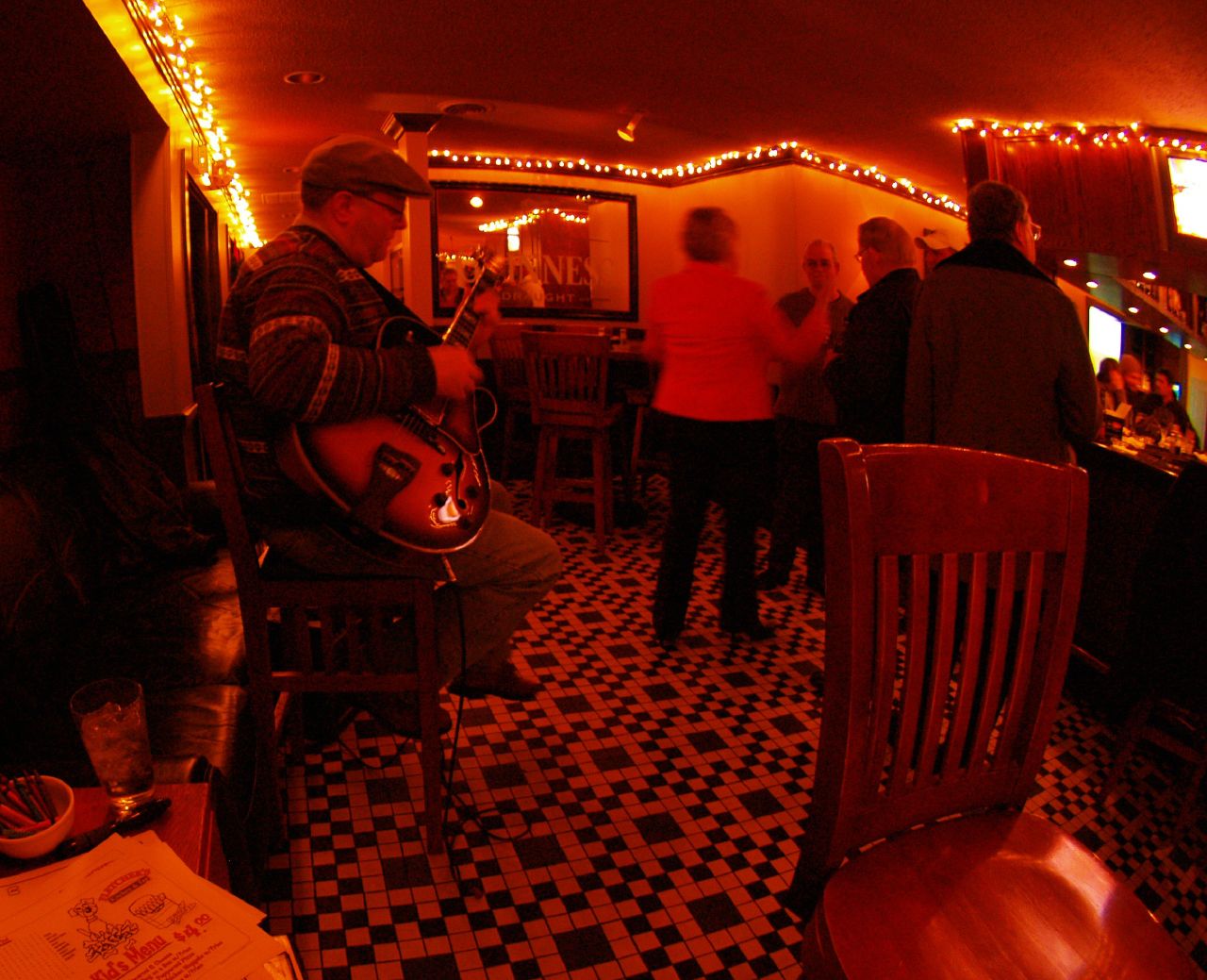 a man plays guitar in a bar with people