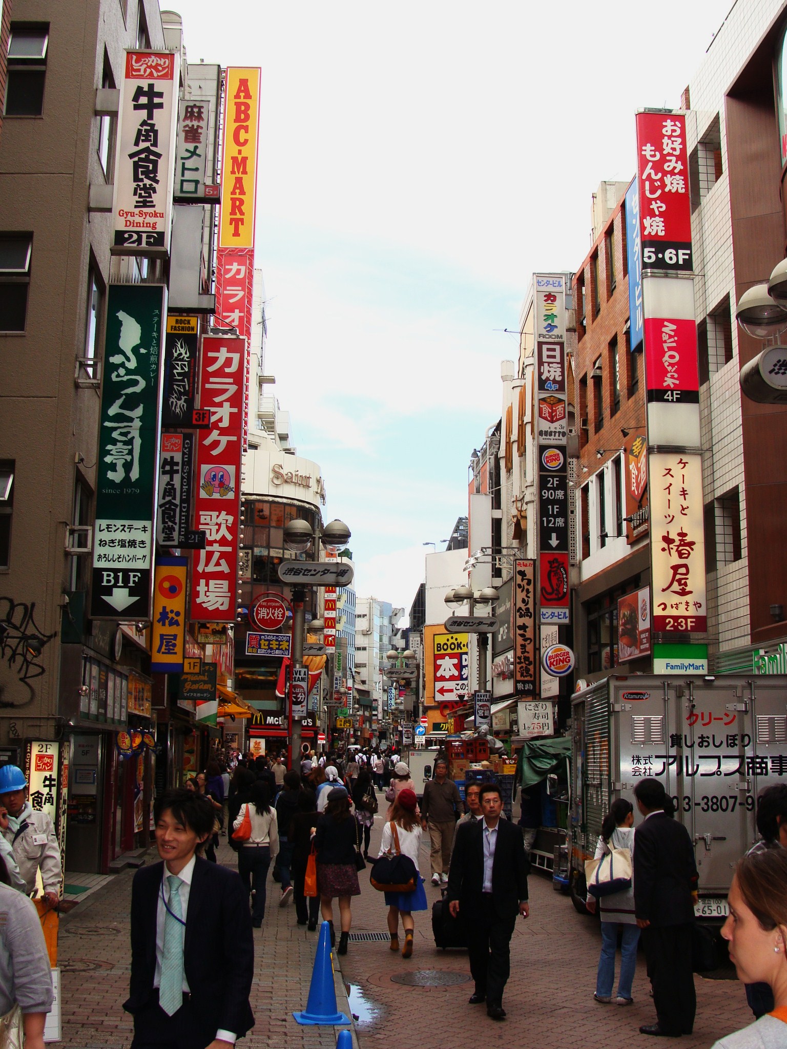 a crowded asian street lined with signs and people
