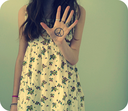 a girl in a dress is posing with her hands together and the peace sign drawn on her hand
