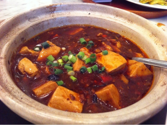 a bowl of a stew with tofu in it, sitting on a table