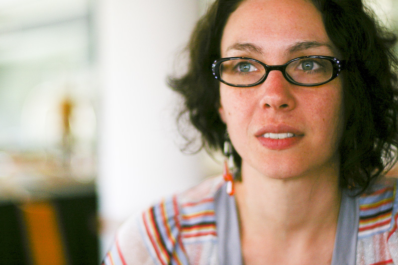 a woman with glasses on looks off into the distance