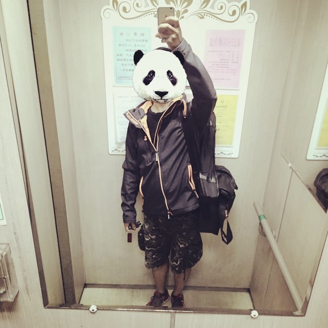 a man with a panda face covering his head, in a subway