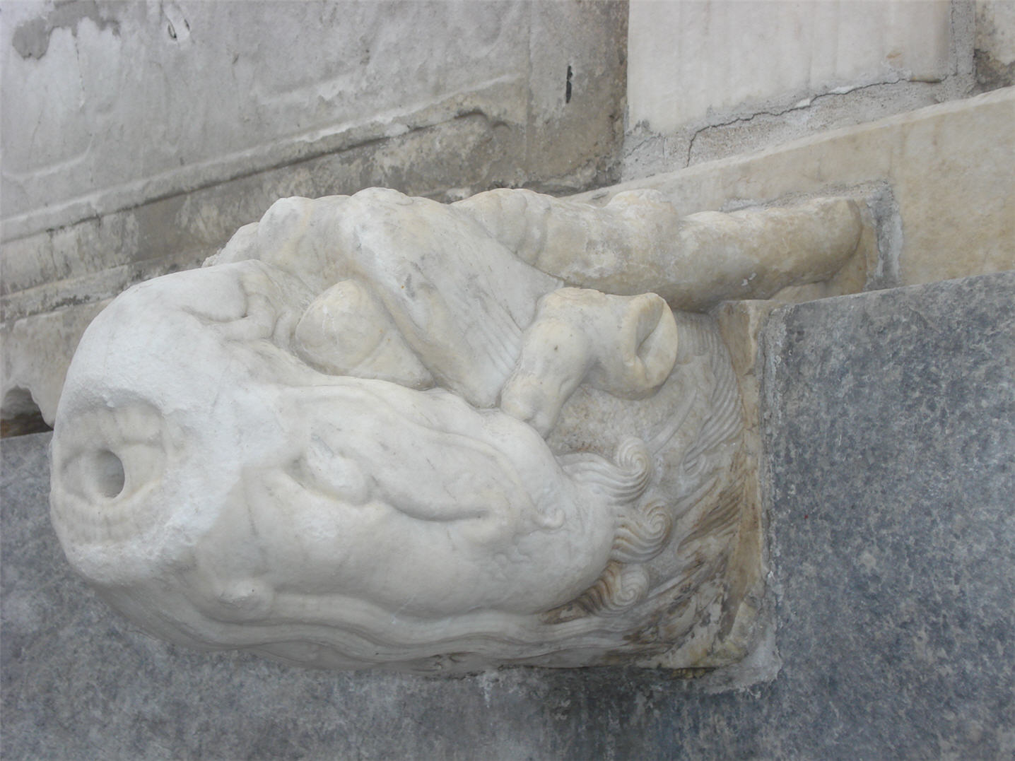 statue in front of stone facade of building with grey pattered walls