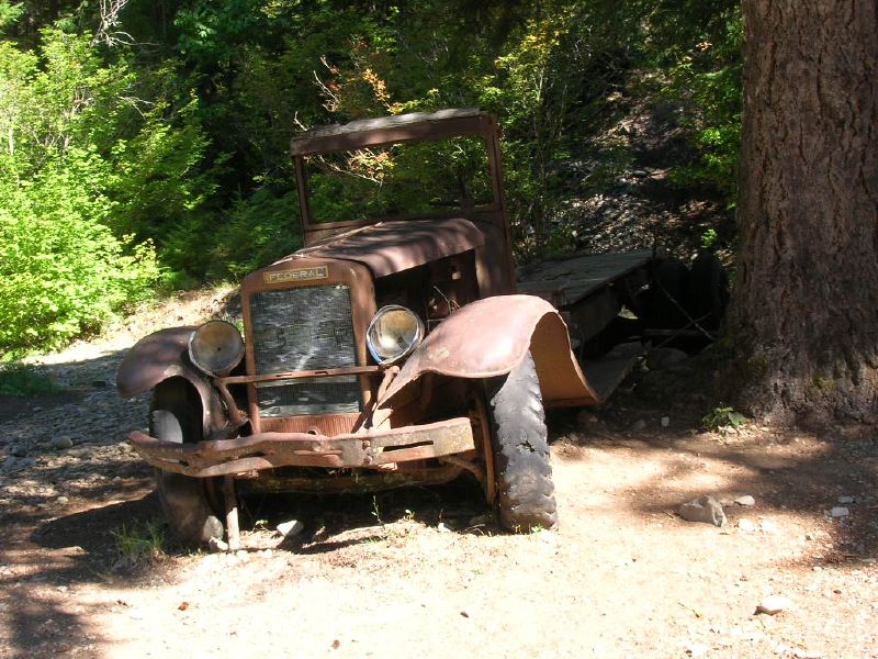 an old rusted vehicle parked in the woods