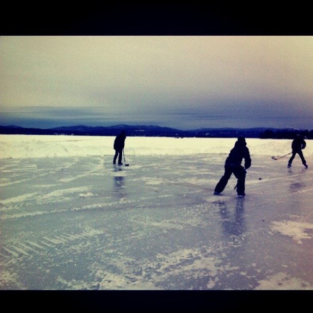 two ice hockey players in black clothes on an icy lake