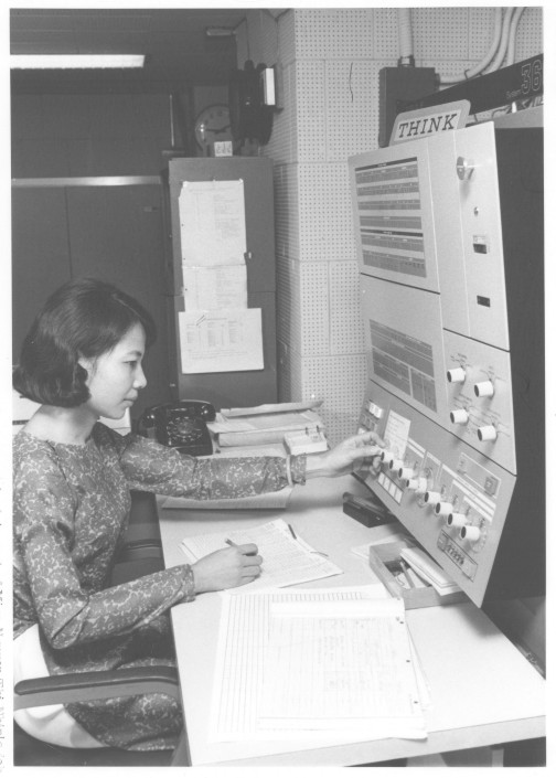 a young woman sitting at a computer desk working on her computer