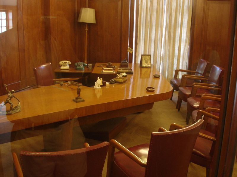 an office with a large table, red leather chairs, and brown wood paneling