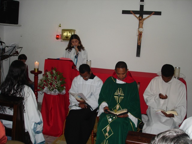 people dressed in white, red and green pray during mass