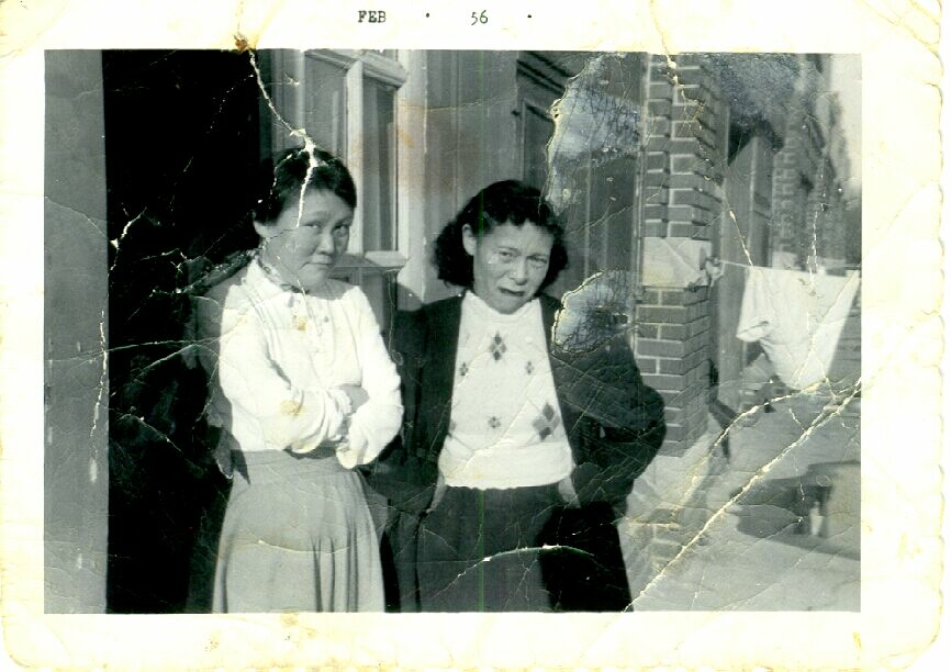 two women are standing outside with their arms folded