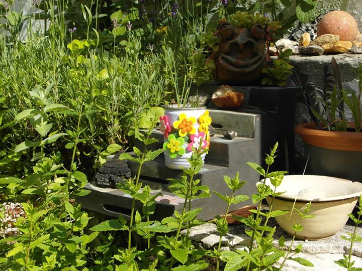 flowers and pots are on top of an old tv in a garden