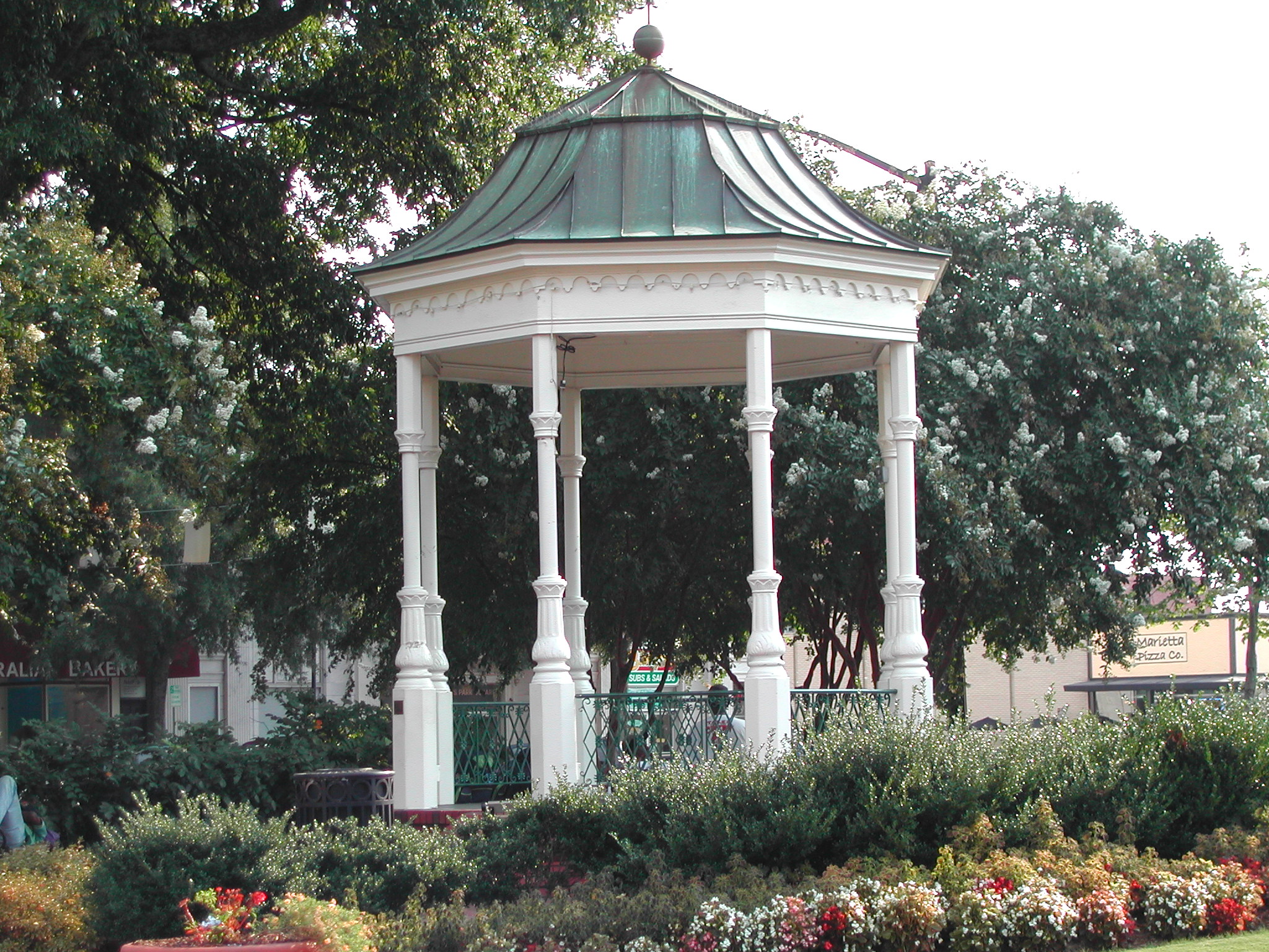 a beautiful wooden gazebo surrounded by lots of flowers and plants