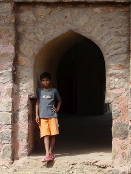 a little boy standing by an archway in a stone building