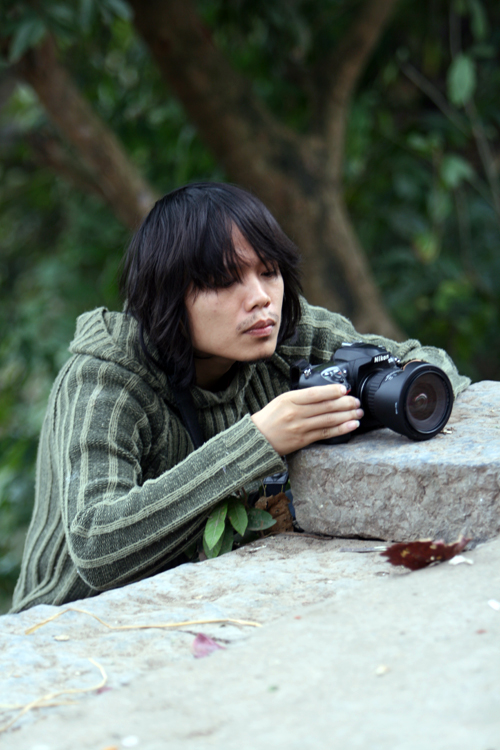 a man holding a camera over a rock