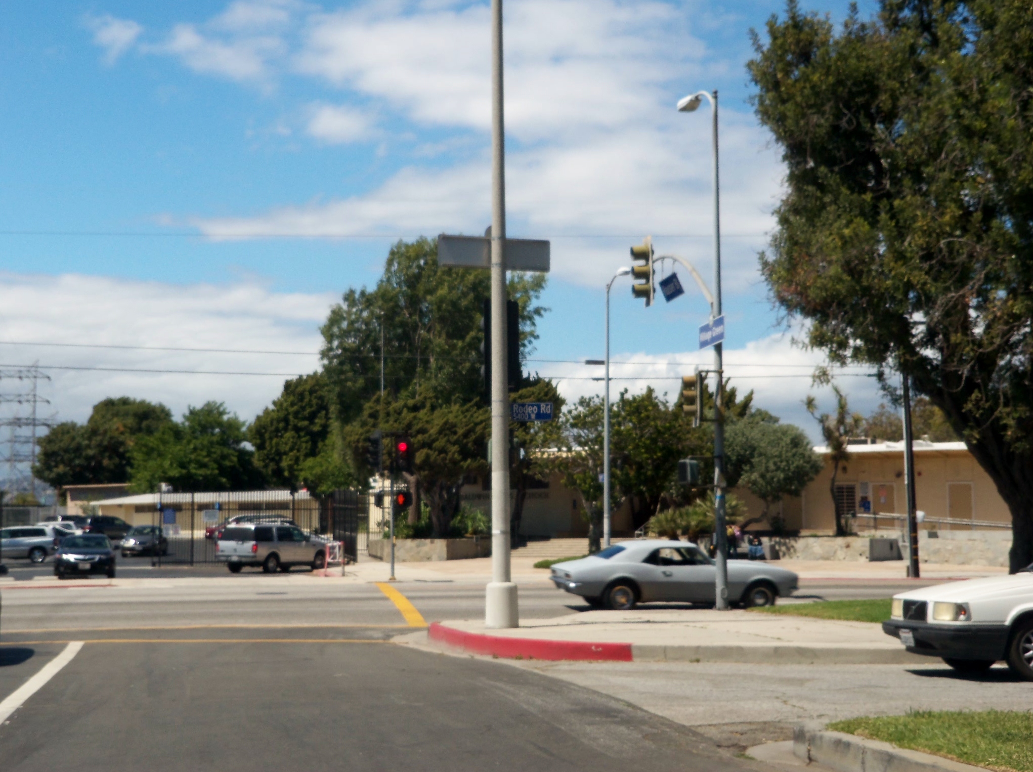 cars at an intersection with street lights, traffic signals, and parking meters