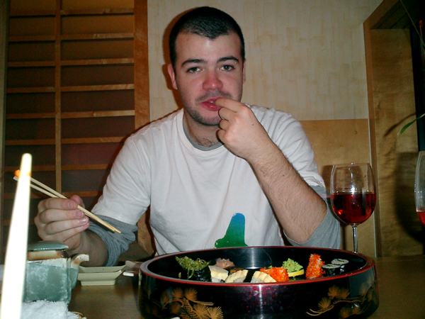 a man sitting at a table eating sushi