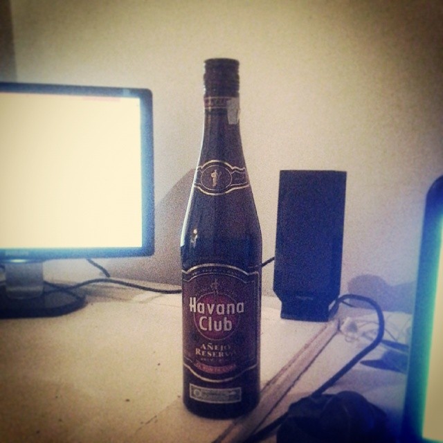 a bottle of havana club is sitting next to a monitor