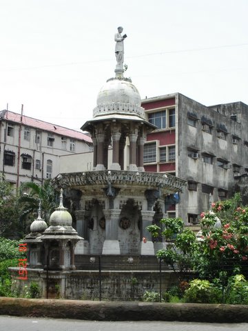 a fountain in the middle of an intersection surrounded by old buildings