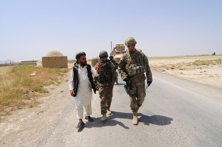 three soldiers walking down the street on a dirt road