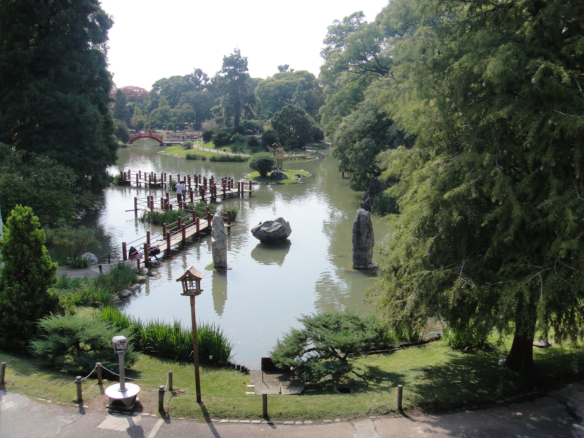 people walk along the water next to a park