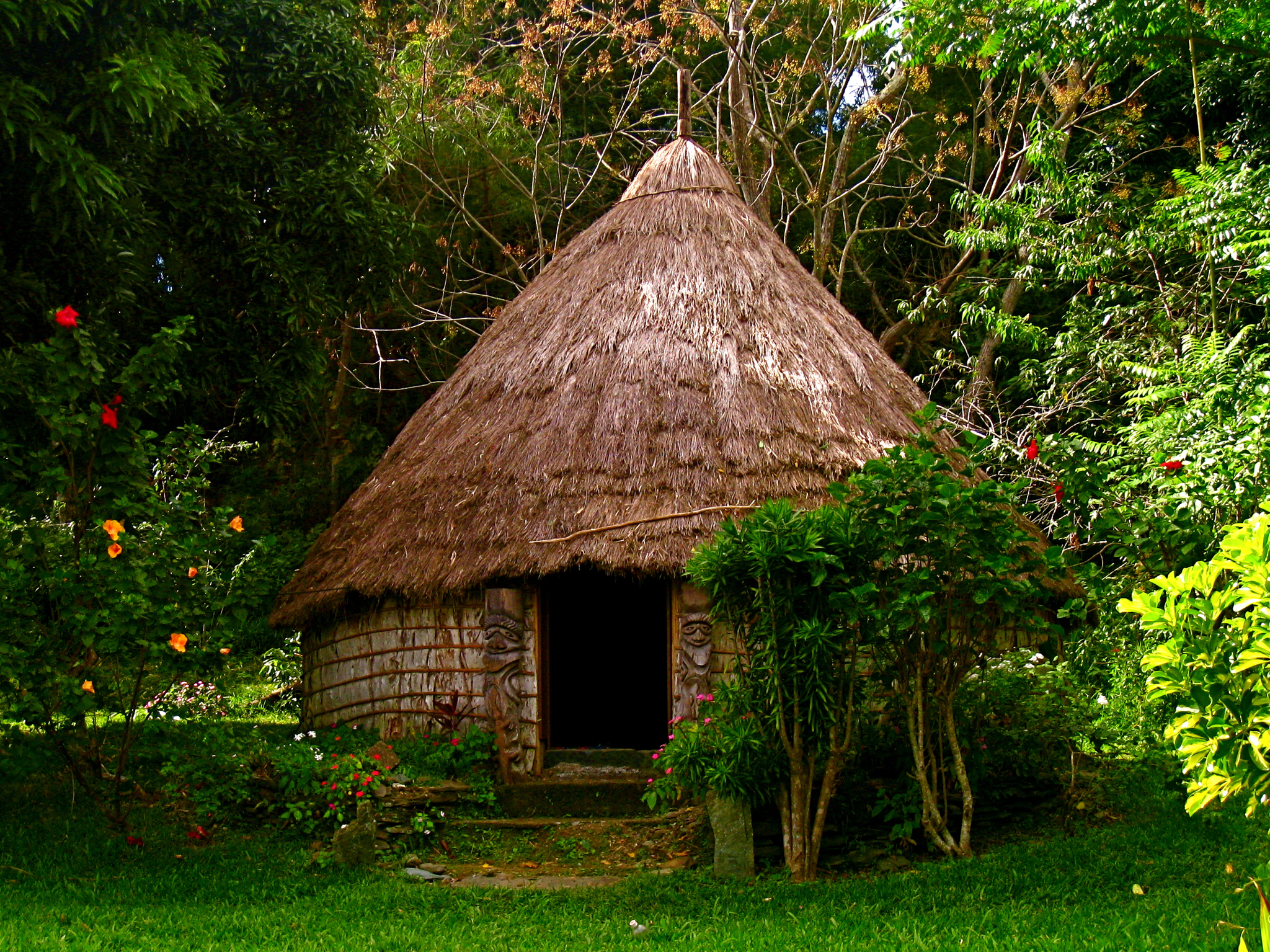an old thatched hut nestled in a lush green forest