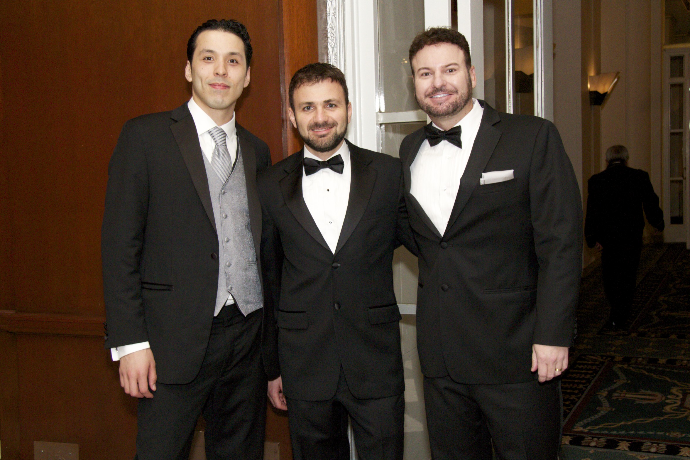 three men dressed in suits posing for the camera