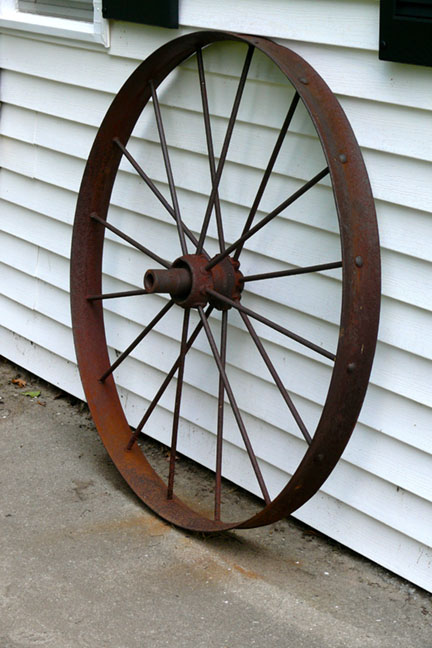 a large wagon wheel leaning up against the side of a house