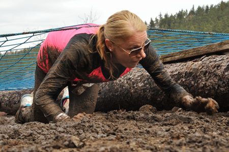 a woman in the mud pulling some logs