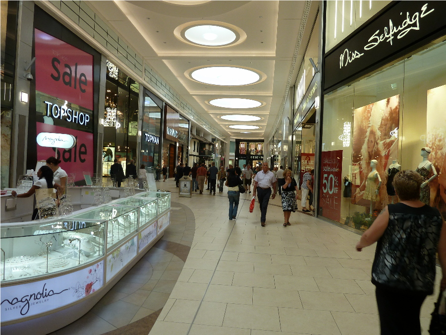 some people shopping inside a mall with a large sign