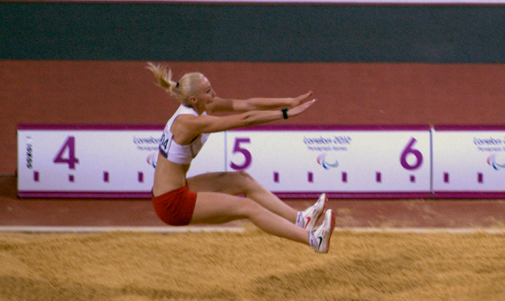 woman in white shirt and red shorts doing stunts on a dirt surface