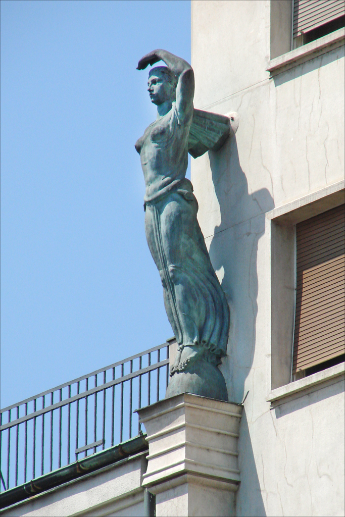 a statue of a man holding an apple stands on top of the corner of a building