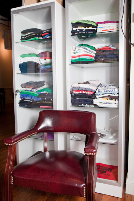 a chair is sitting in front of a glass cabinet filled with clothes